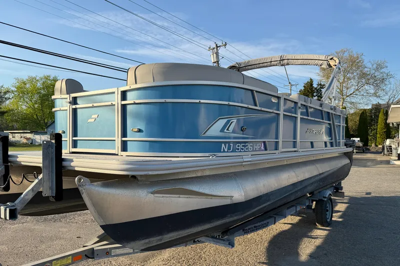 Slide: The Image of 2018 Starcraft EX 22 C SG pontoon boat on trailer, blue exterior, parked outdoors. - 7