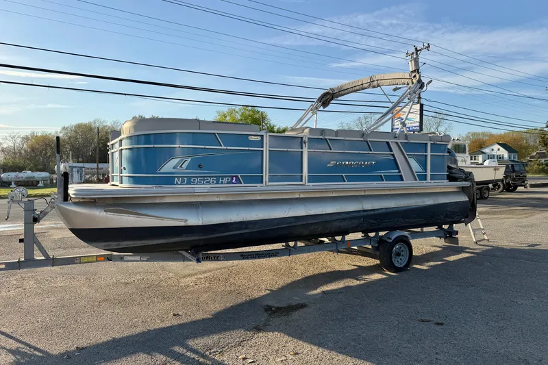 Slide: The Image of 2018 Starcraft EX 22 C SG pontoon boat on trailer, parked outdoors. - 9