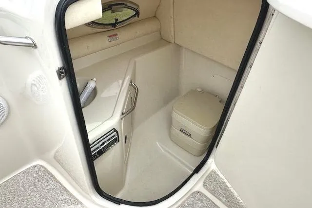 Slide: The Image of 2004 Sea Ray 270 Sundeck interior with compact marine toilet and storage space. - 22