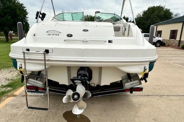 Slide: The Image of 2004 Sea Ray 270 Sundeck boat, rear view, parked on concrete with visible propeller. - 7