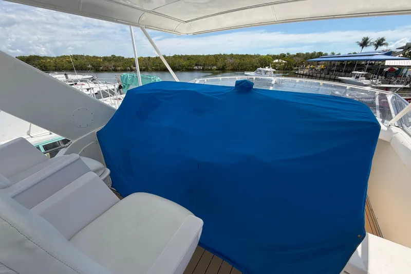 Slide: The Image of 1986 Bertram 46 Convertible yacht deck with blue-covered equipment, marina view. - 100
