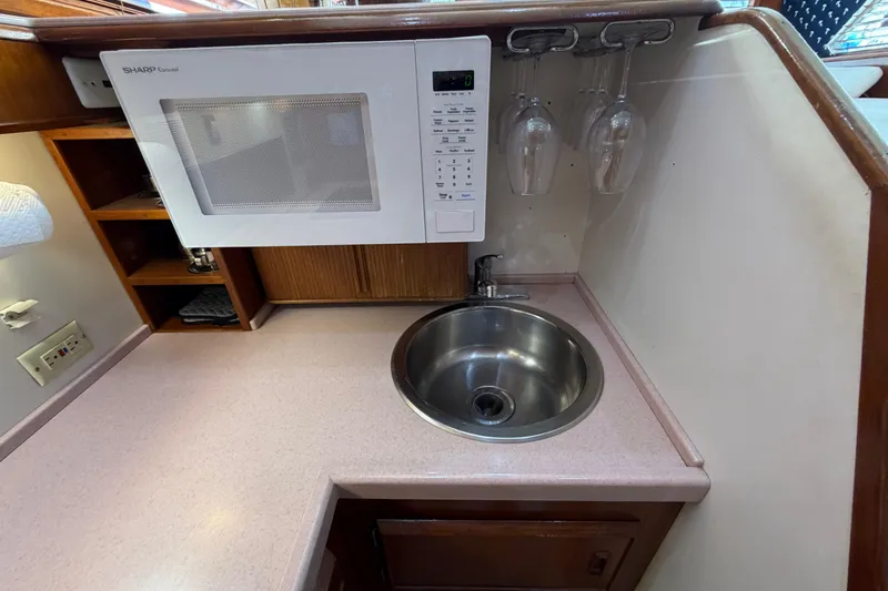 Slide: The Image of Compact kitchen area in a 1986 Bertram 46 Convertible yacht with microwave and sink. - 19