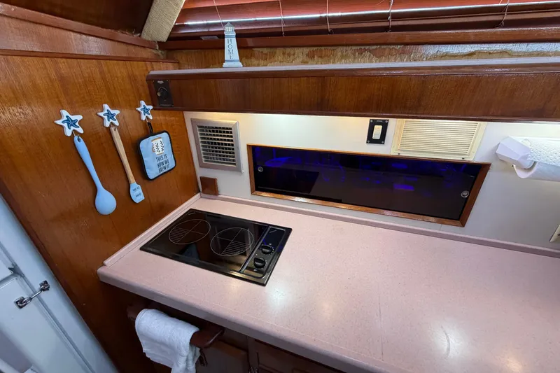 Slide: The Image of 1986 Bertram 46 Convertible yacht kitchen with stove, wooden decor, and nautical-themed utensils. - 20