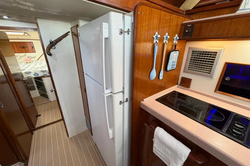 Slide: The Image of 1986 Bertram 46 Convertible yacht kitchen with stove, refrigerator, and wooden cabinetry. - 21
