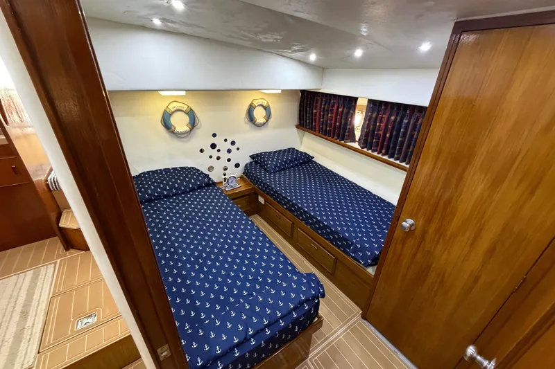 Slide: The Image of Interior of 1986 Bertram 46 Convertible yacht with twin beds and nautical decor. - 24
