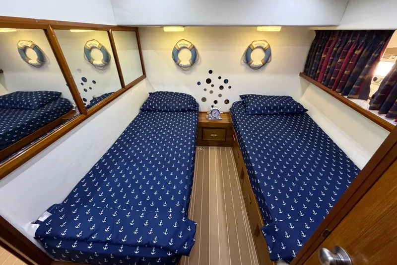 Slide: The Image of Twin beds with nautical-themed bedding in a 1986 Bertram 46 Convertible cabin. - 25