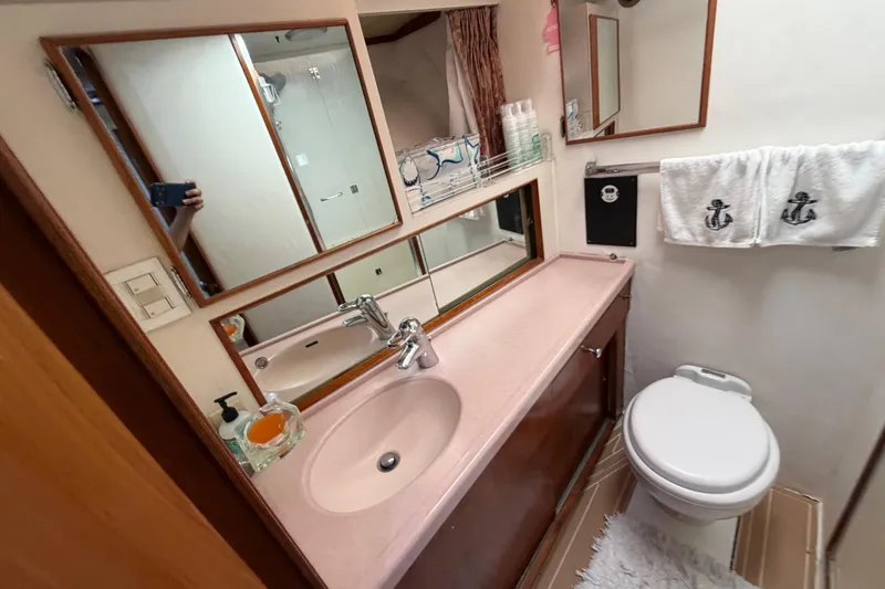 Slide: The Image of Bathroom interior of 1986 Bertram 46 Convertible yacht with sink, mirror, and nautical-themed towels. - 29
