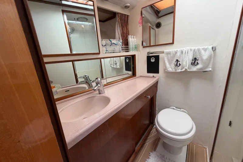 Slide: The Image of Bathroom interior of 1986 Bertram 46 Convertible yacht, featuring sink, toilet, and nautical-themed towels. - 30