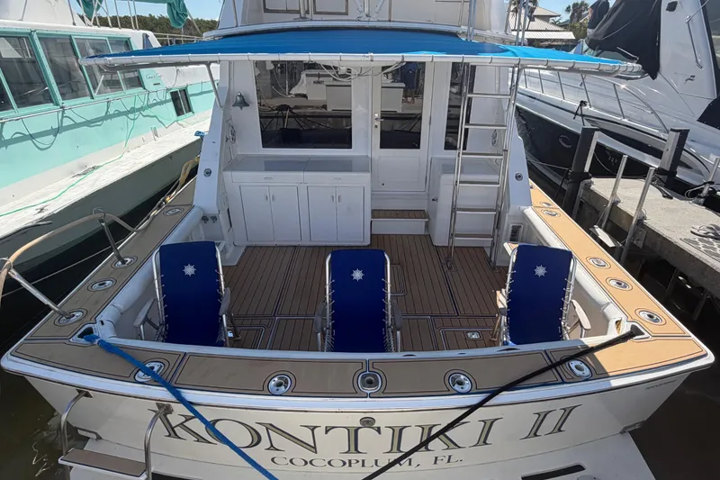 Slide: The Image of 1986 Bertram 46 Convertible yacht docked, featuring a spacious deck with blue chairs. - 44