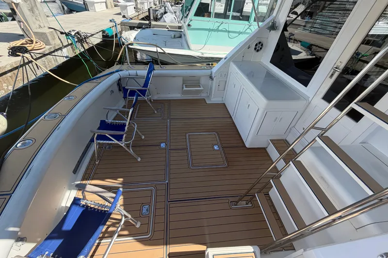 Slide: The Image of 1986 Bertram 46 Convertible yacht deck with chairs and storage, docked at marina. - 46