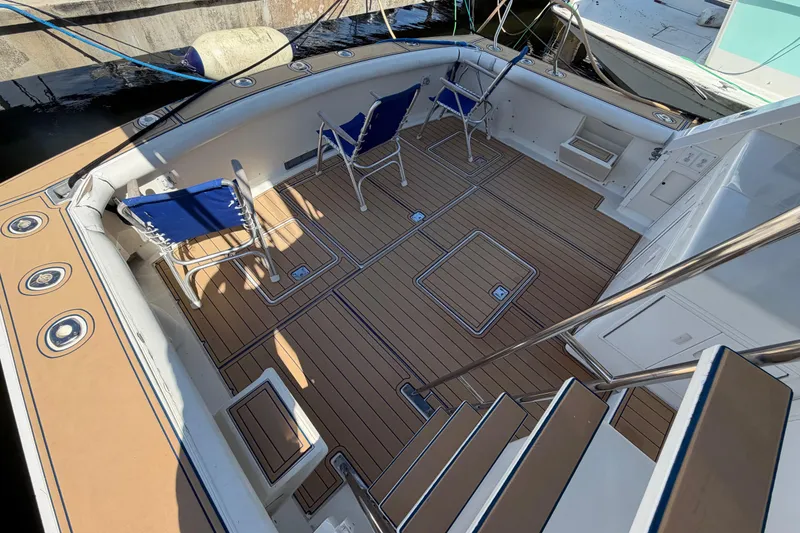 Slide: The Image of 1986 Bertram 46 Convertible yacht deck with chairs and wooden flooring. - 47