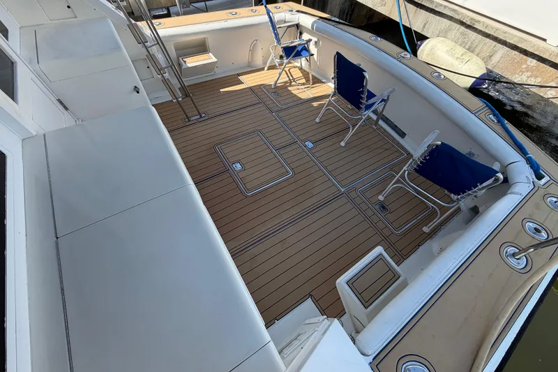 Slide: The Image of 1986 Bertram 46 Convertible yacht deck with chairs and wooden flooring. - 48