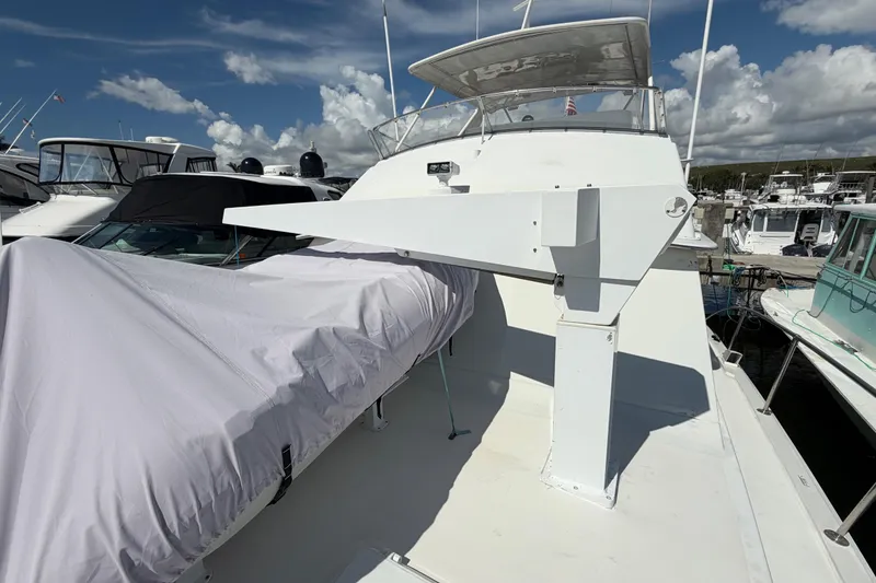 Slide: The Image of 1986 Bertram 46 Convertible yacht deck with covered equipment, docked at marina under blue sky. - 64