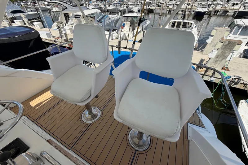 Slide: The Image of Two white captain chairs on a 1986 Bertram 46 Convertible yacht deck. - 69