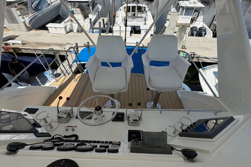 Slide: The Image of 1986 Bertram 46 Convertible yacht helm with dual seats and control panel at marina. - 70