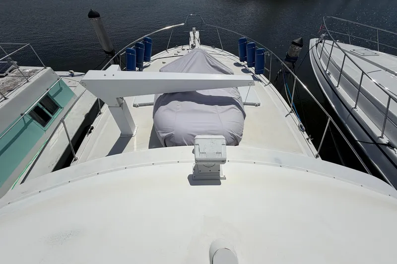 Slide: The Image of 1986 Bertram 46 Convertible yacht deck with covered equipment, docked beside other boats. - 84