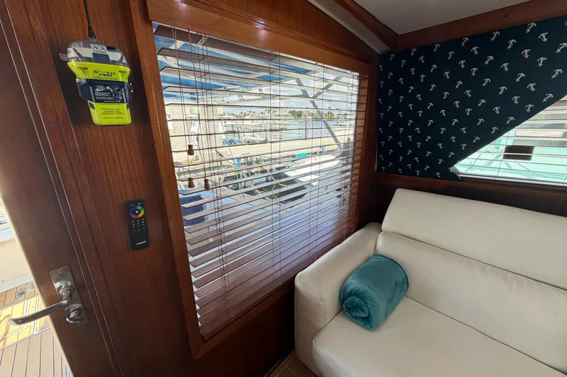 Slide: The Image of Interior of a 1986 Bertram 46 Convertible yacht with a white sofa and wooden blinds. - 99