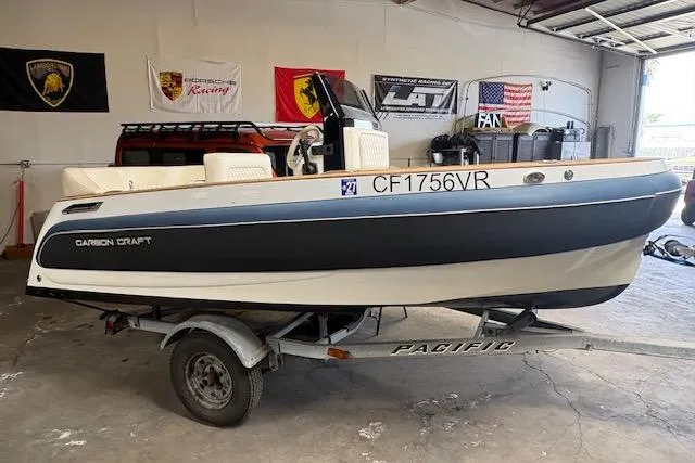 Slide: The Image of 2018 Carbon Craft C130 boat on trailer in garage with racing banners. - 2