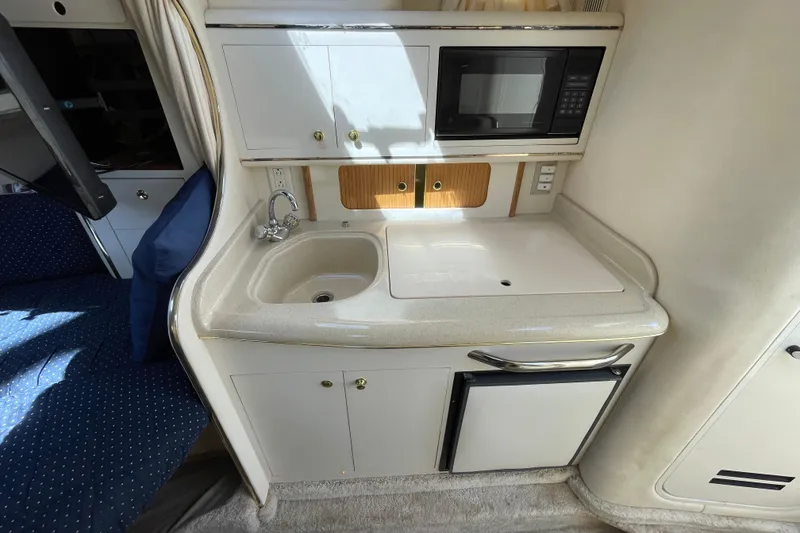 Slide: The Image of 1999 Sea Ray 290 Sundancer cockpit with beige seating and glass windshield, docked in marina. - 19