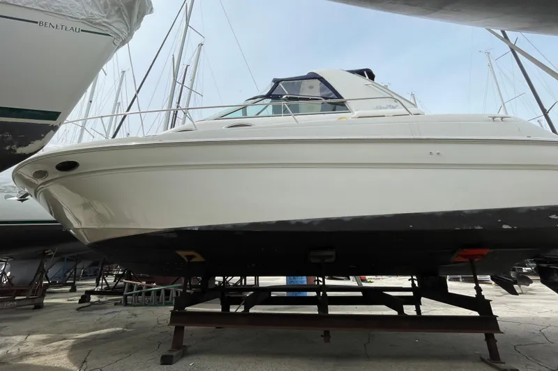 Slide: The Image of 1999 Sea Ray 290 Sundancer boat on dry dock, surrounded by other vessels. - 3