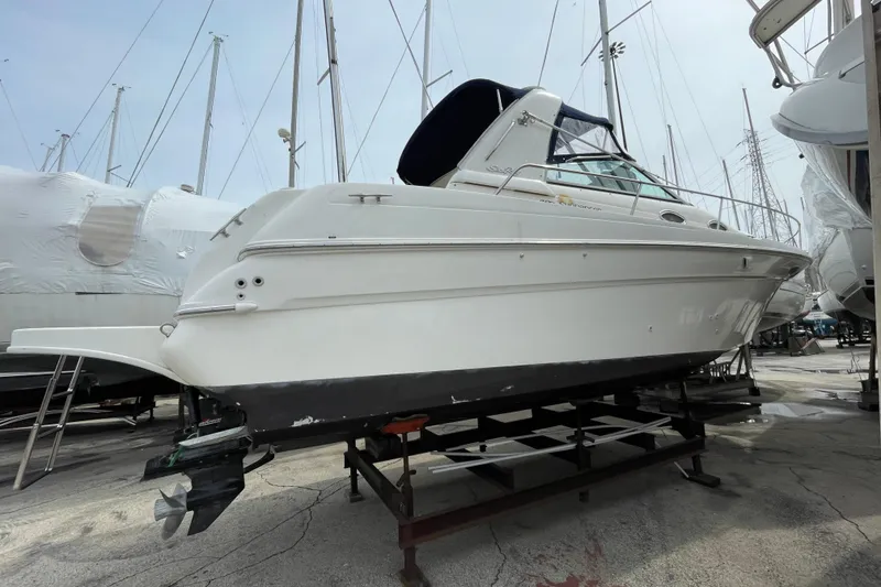 Slide: The Image of 1999 Sea Ray 290 Sundancer boat on dry dock, side view with marina background. - 4