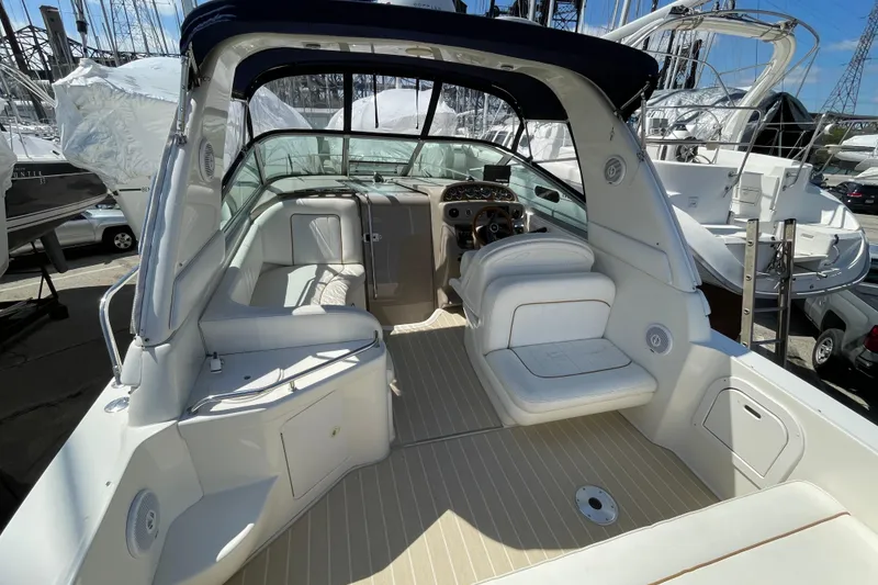 Slide: The Image of 1999 Sea Ray 290 Sundancer boat interior with white seating and helm, docked at marina. - 7