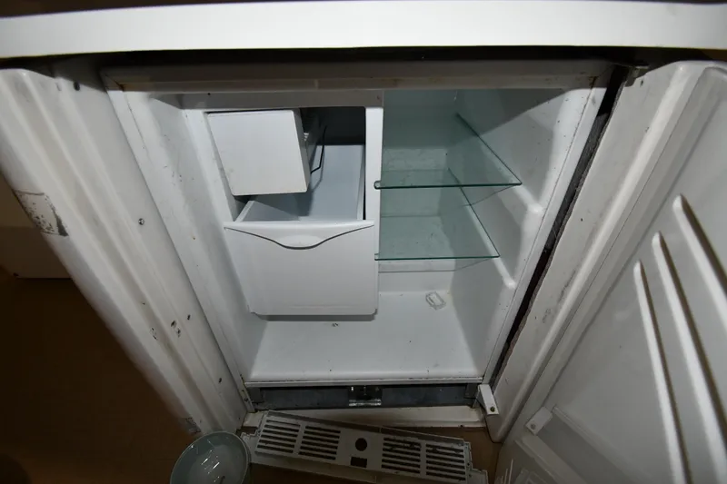Slide: The Image of Open refrigerator inside a 2003 Cruisers Yachts 5000 Sedan Sport, showing empty shelves. - 28