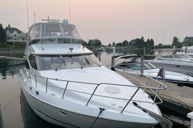Slide: The Image of 2003 Cruisers Yachts 5000 Sedan Sport docked at a marina, surrounded by calm water. - 3