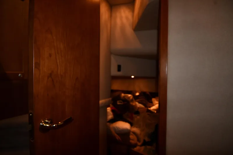 Slide: The Image of Interior cabin view of 2003 Cruisers Yachts 5000 Sedan Sport, featuring wooden door and cozy bedding. - 49