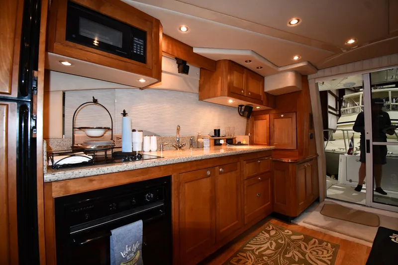 Slide: The Image of Luxurious kitchen interior of 2003 Cruisers Yachts 5000 Sedan Sport with wooden cabinetry. - 54