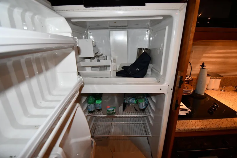 Slide: The Image of Open refrigerator inside 2003 Cruisers Yachts 5000 Sedan Sport, showing shelves and bottled drinks. - 58