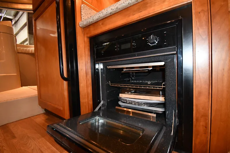 Slide: The Image of 2003 Cruisers Yachts 5000 Sedan Sport kitchen with open oven and wooden cabinetry. - 68