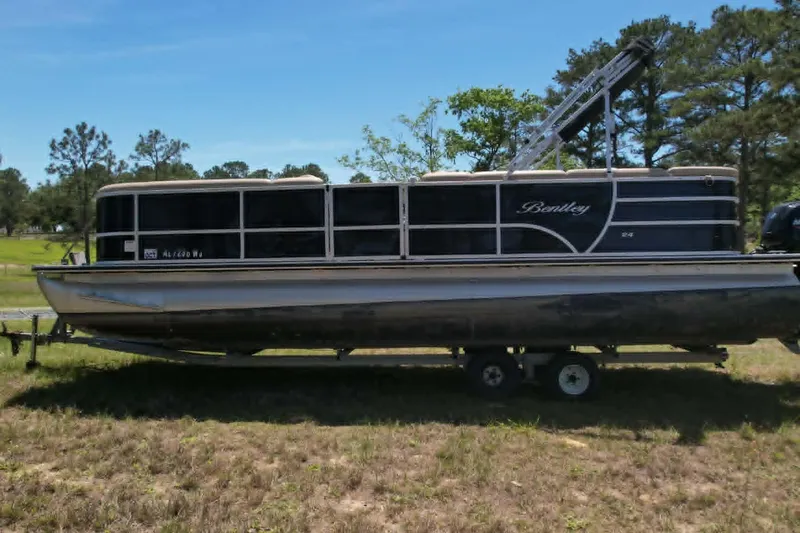 Slide: The Image of 2022 Bentley Pontoons 240 CRUISE on trailer, parked on grassy area with trees in background. - 3