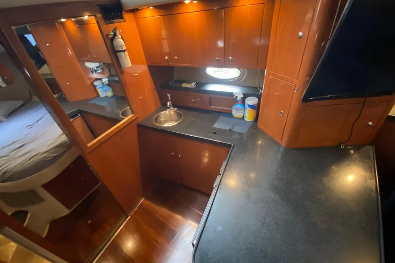 Slide: The Image of 2006 Regal Commodore 3880 yacht interior with kitchenette, sink, and wooden cabinetry. - 35