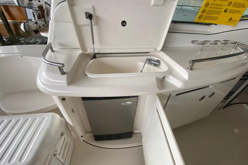 Slide: The Image of 2005 Sea Ray 500 Sundancer yacht kitchenette with sink, mini fridge, and storage cabinets. - 15