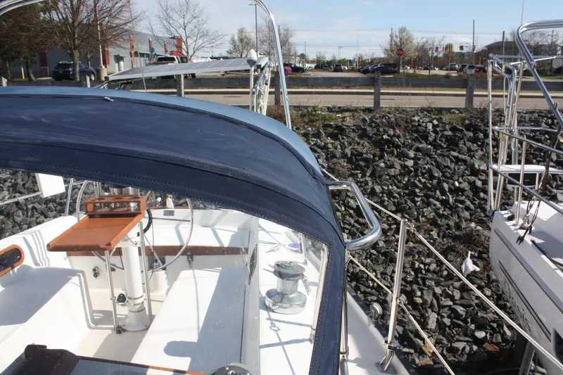 Slide: The Image of 1986 Catalina 36 sailboat cockpit with blue canopy, docked near rocky shoreline. - 24