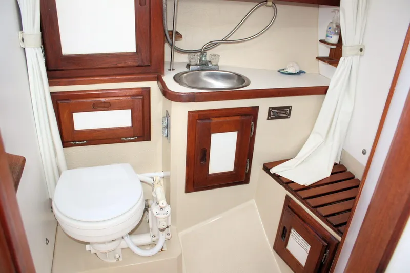 Slide: The Image of 1986 Catalina 36 yacht bathroom with wooden cabinets, sink, and marine toilet. - 38