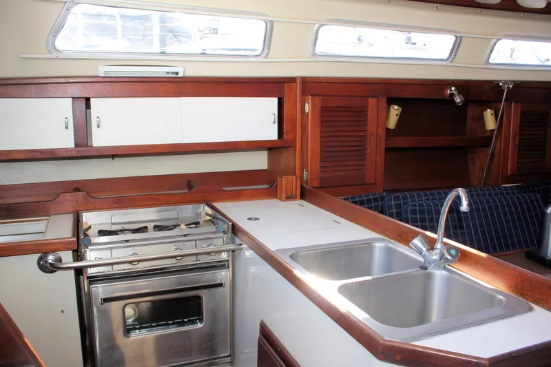 Slide: The Image of 1986 Catalina 36 yacht kitchen with wooden cabinets, dual sink, and stove. - 51