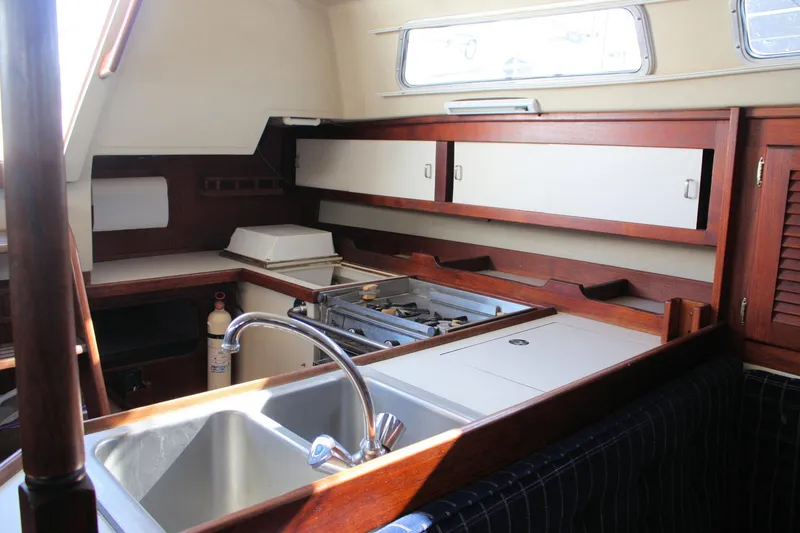 Slide: The Image of Interior of 1986 Catalina 36 sailboat kitchen with sink, stove, and wooden cabinetry. - 52