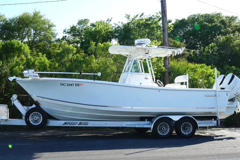 Slide: The Image of 2004 Regulator 26 Classic boat on trailer, parked near lush greenery. - 10