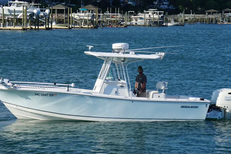 Slide: The Image of 2004 Regulator 26 Classic boat on water near docks, with person onboard. - 3