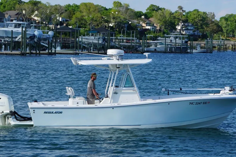 Slide: The Image of 2004 Regulator 26 Classic boat cruising near a marina with docks and houses in the background. - 4