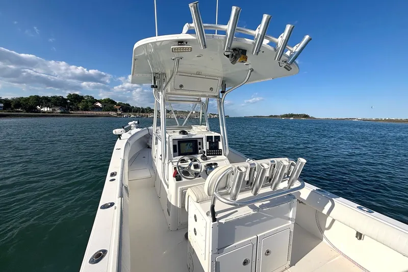 Slide: The Image of 2004 Regulator 26 Classic boat on calm water, featuring a spacious deck and fishing rod holders. - 6