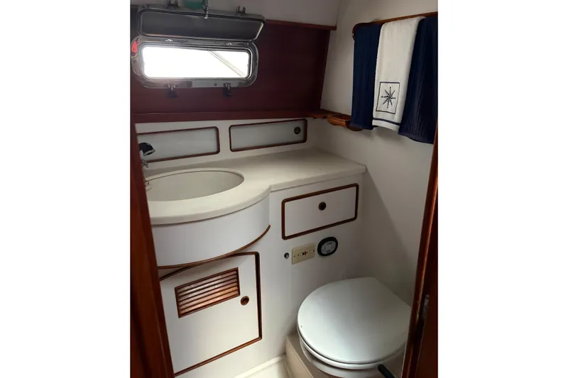 Slide: The Image of 1990 Little Harbor 36 yacht bathroom with sink, toilet, and nautical-themed towels. - 12