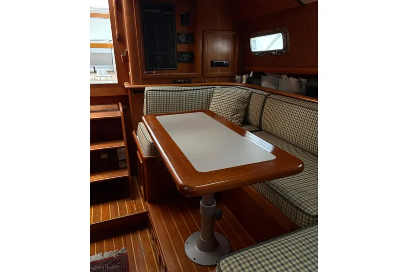 Slide: The Image of Cozy interior of a 1990 Little Harbor 36 sailboat with wooden table and checkered seating. - 8