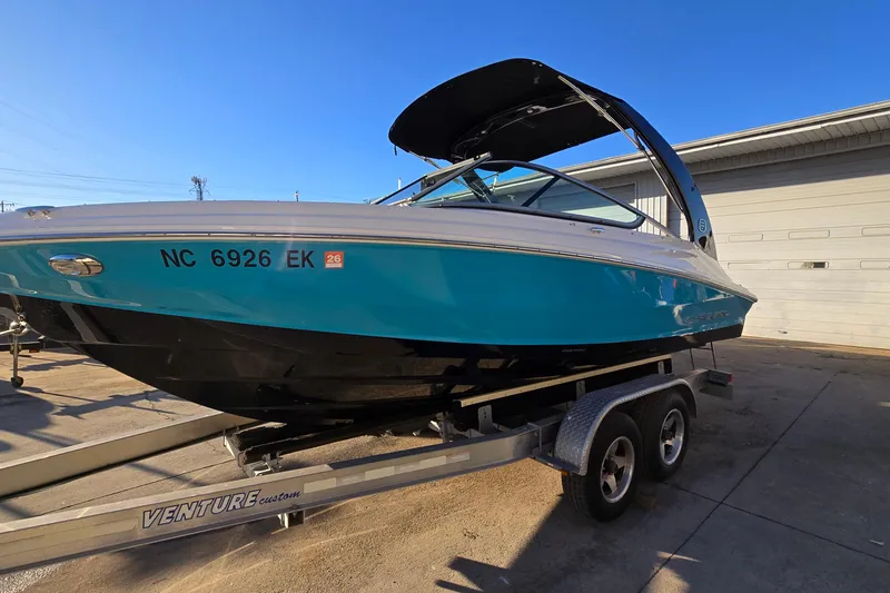 The Image of 2019 Regal 2000 ES Bowrider on trailer, vibrant blue hull, parked outdoors. - 0