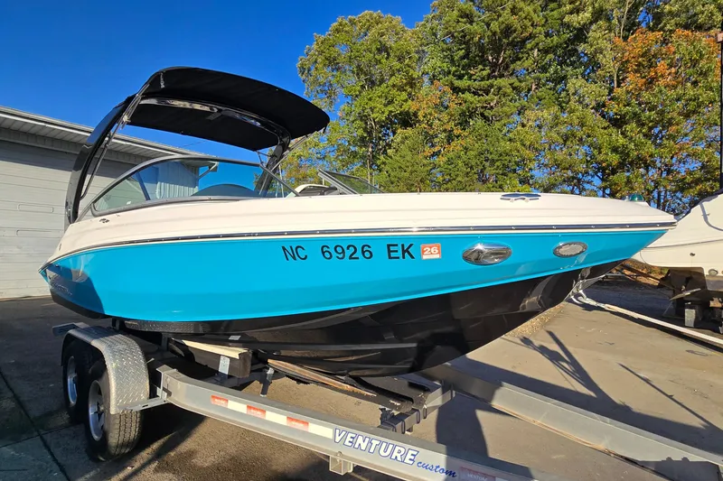 Slide: The Image of 2019 Regal 2000 ES Bowrider boat on trailer, vibrant blue hull, parked outdoors. - 2