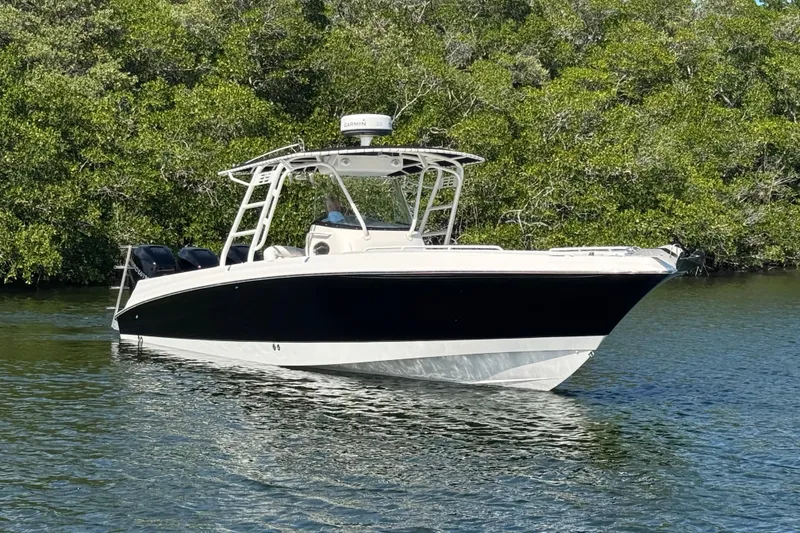 Slide: The Image of 2014 Wellcraft 35 Scarab Tournament boat on calm water, surrounded by lush greenery. - 6