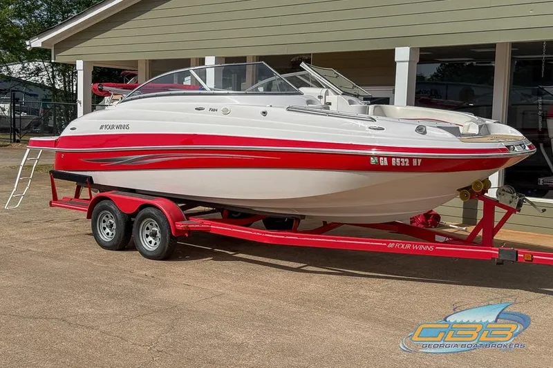 Slide: The Image of 2008 Four Winns F224 boat on red trailer, parked outside a building. - 21