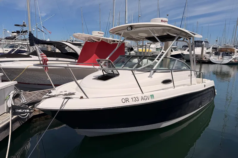 The Image of 2008 Robalo R225 Walkaround boat docked in a marina, surrounded by other vessels. - 0